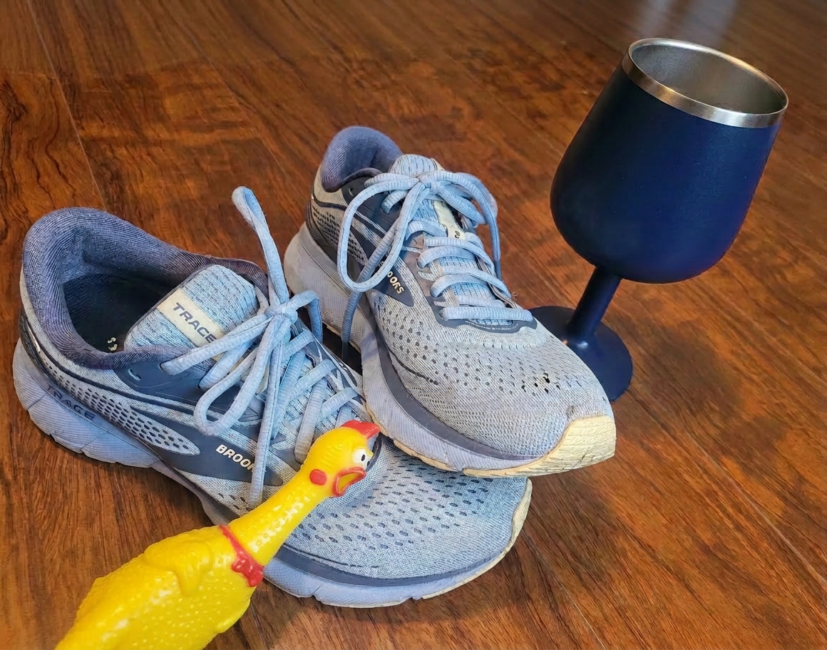 image Running shoes beside a wine goblet with a rubber chicken leaning in, creating a funny post‑run flat lay.