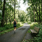 Woman running on paved path in dense green forest